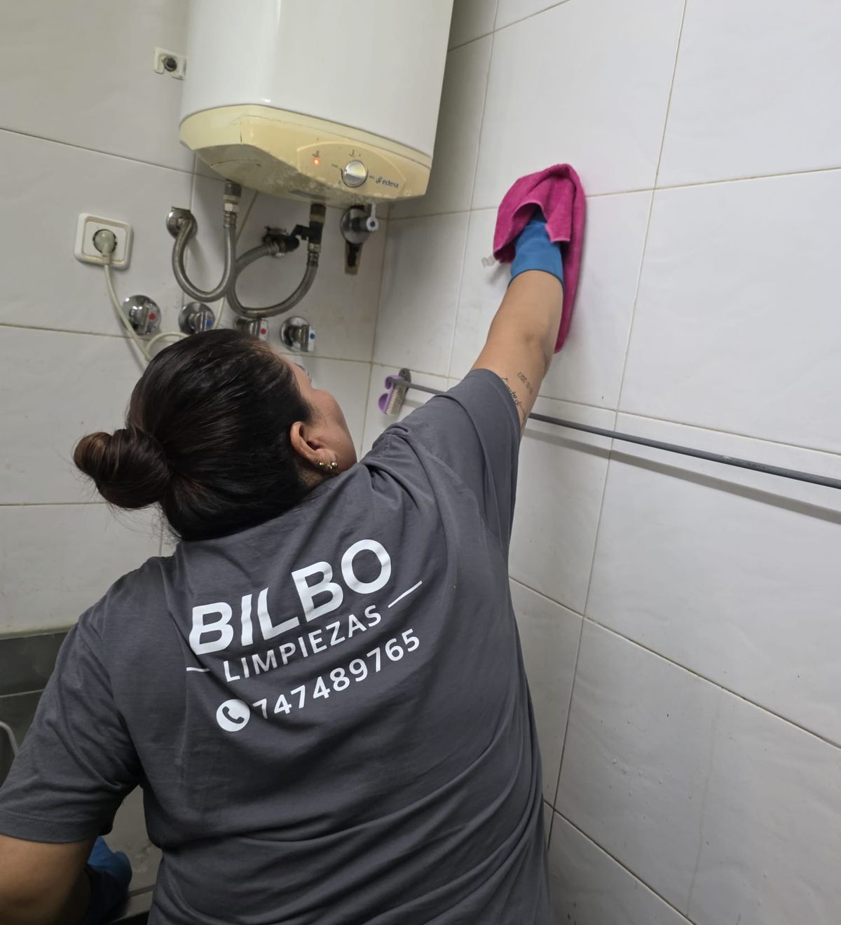 Operaria de Bilbo Limpieza con la camiseta de la empresa limpiando los azulejos de una cocina en Bilbao
